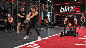 Coach leading a small group through a kettlebell and sled circuit on the Blitz45 strength floor